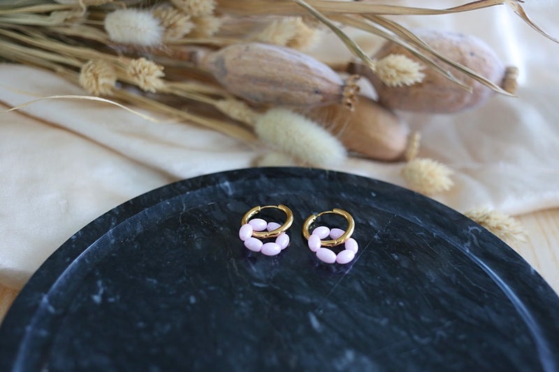 Hieman soikean malliset puuteriroosat lasihelmet kullatuissa huggie-renkaissa.